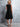 Woman wearing a black dress against a gray concrete wall
