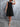 Woman wearing a black dress against a gray wall