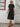Woman wearing a black dress standing against a white wall