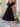 Woman wearing a black dress standing outdoors on a stone patio