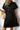 Woman wearing a black dress with a white wall background