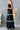 Woman wearing a black dress with white stripes in a minimalistic setting