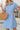 Woman wearing a blue dress holding a straw bag indoors