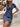Woman wearing a blue dress sitting on steps with a neutral background