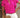 Woman wearing a bright pink blouse with ruffled sleeves and white shorts, holding a straw clutch