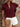 Woman wearing a burgundy ruffled blouse with white shorts, holding a beige clutch