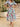 Woman wearing a colorful floral dress standing on stone steps outdoors