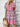 Woman wearing a colorful patterned dress against a white brick wall