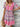 Woman wearing a colorful patterned dress against a wooden background