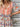 Woman wearing a colorful red patterned dress with a wooden background, close up