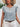 Woman wearing a floral blouse and white pants with a blurred background