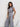 Woman wearing a gray jumpsuit against a white background