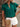 Woman wearing a green blouse with ruffled sleeves and white shorts, holding a beige handbag