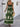 Woman wearing a green boho dress with white patterns, back view