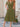 Woman wearing a green dress standing outdoors on a stone patio