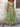 Woman wearing a green floral dress against a textured wall