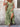 Woman wearing a green floral dress with a stone wall background