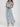 Woman wearing a light blue floral dress holding white flowers on a white background
