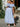 Woman wearing a light blue off-shoulder dress with floral pattern, standing outdoors