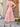Woman wearing a pink dress standing outdoors on a patio
