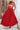 Woman wearing a red and white floral top and red skirt with a straw hat and bag