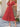 Woman wearing a red dress standing outdoors on a stone patio