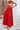 Woman wearing a red floral top and red skirt with a straw bag and hat