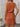 Woman wearing a rust-colored checkered dress indoors