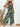 Woman wearing a tropical print jumpsuit with a white background