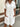 Woman wearing a white button-up dress standing outdoors