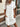 Woman wearing a white button-up dress with a blurred background
