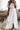 Woman wearing a white lace dress holding a beige bag in a living room