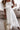Woman wearing a white off-shoulder dress in a living room