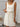 Woman wearing a white sleeveless dress with a textured pattern against a neutral background