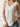 Woman wearing a white sleeveless top and denim shorts against a neutral background
