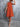 Woman wearing an orange dress against a gray background
