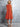 Woman wearing an orange dress against a gray concrete wall