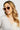 Woman wearing round sunglasses with a neutral background