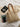 Woven straw tote bag with tan leather straps displayed on a cream blazer, next to an iPad, black smartphone, and a book titled "Metaphorical Concepts," all placed on a white bed