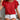 Person wearing a red ruffled top and white shorts against a neutral background
