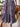 zoomed-in patterned dress holding a woven bag indoors